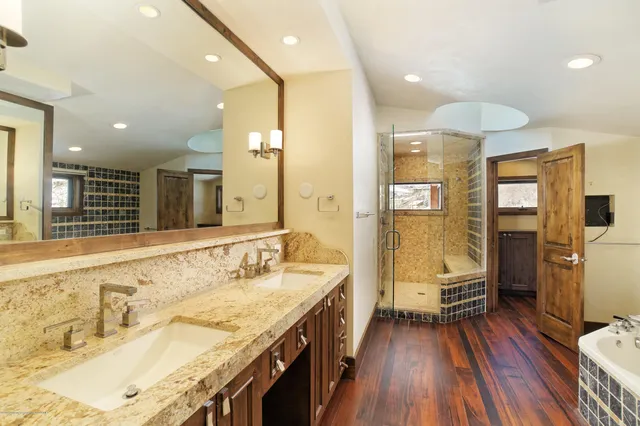 a spacious bathroom with a granite countertop double vanity sink a mirror and a shower