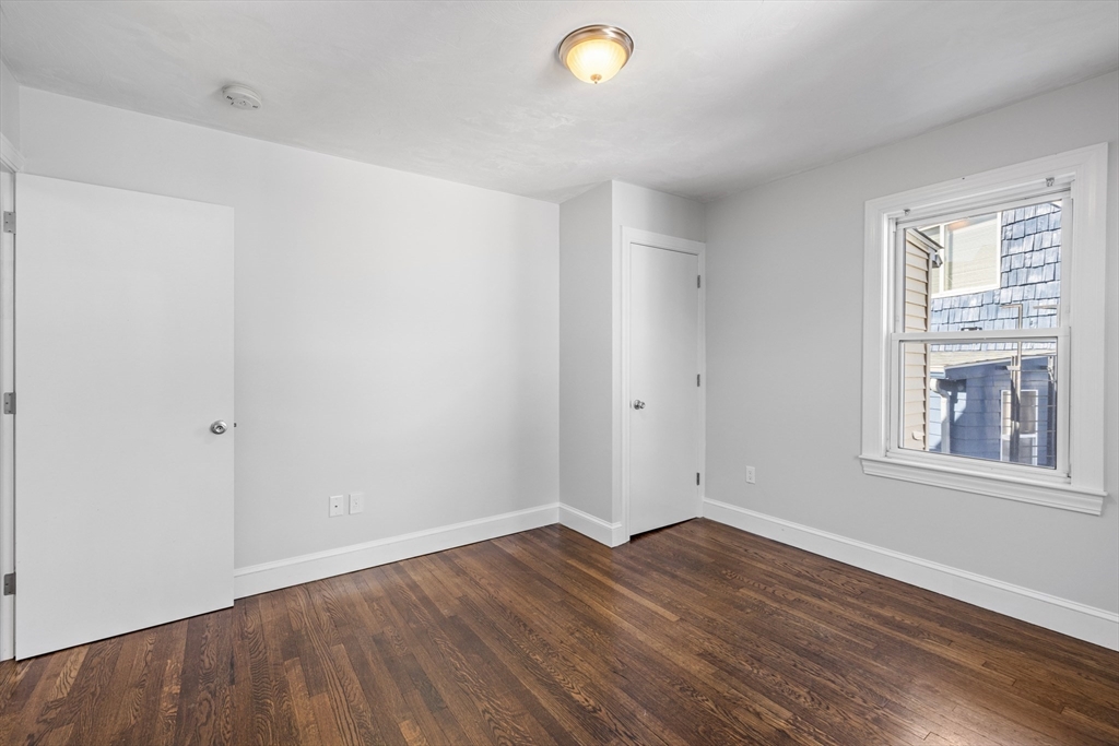 48 High Street, Unit 48 Somerville, MA 02144 - Photo 11 of 23 an empty room with wooden floor and windows