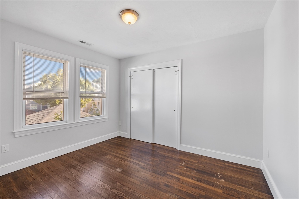 48 High Street, Unit 48 Somerville, MA 02144 - Photo 12 of 23 an empty room with wooden floor and windows