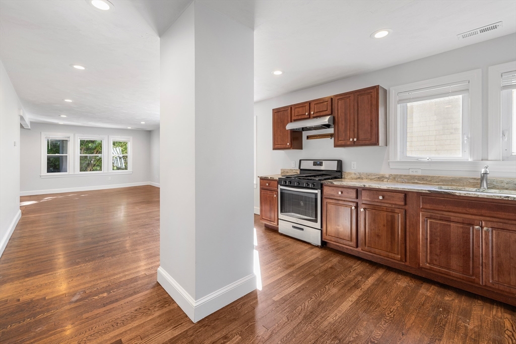 48 High Street, Unit 48 Somerville, MA 02144 - Photo 6 of 23 a kitchen with granite countertop wooden floors and stainless steel appliances