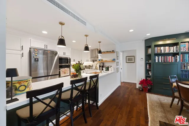 a kitchen with stainless steel appliances kitchen island granite countertop a dining table chairs refrigerator and sink