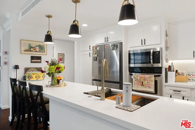 a kitchen with stainless steel appliances granite countertop a sink and a refrigerator