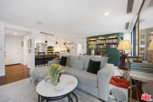 a living room with furniture kitchen view and a large window