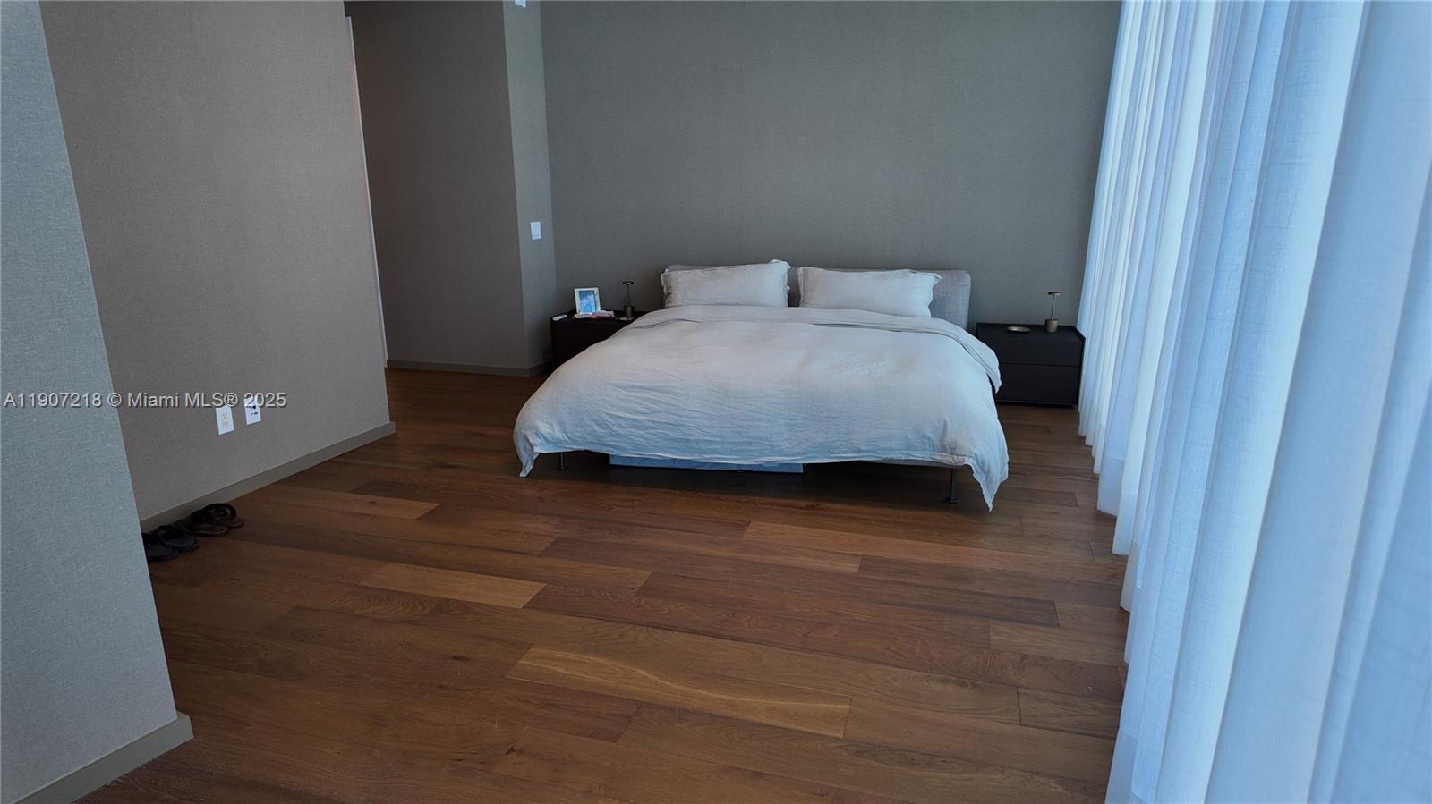 18555 Collins Avenue, Unit 905 Sunny Isles Beach, FL 33160 - Photo 12 of 38 a bedroom with a bed and wooden floor