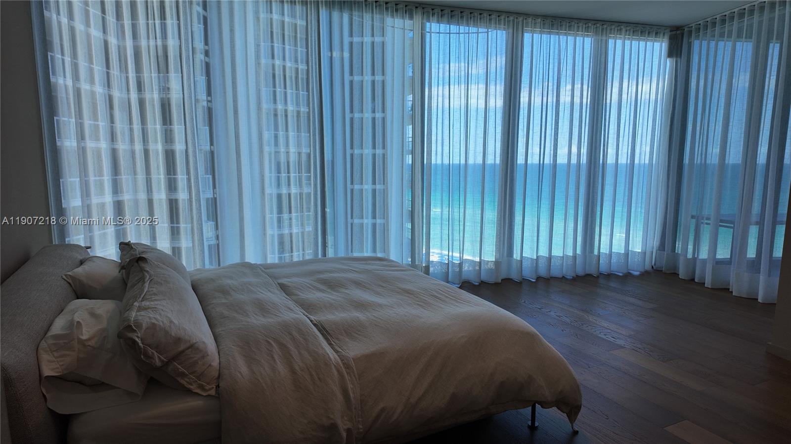 18555 Collins Avenue, Unit 905 Sunny Isles Beach, FL 33160 - Photo 14 of 38 a bed sitting in a spacious bedroom next to a window