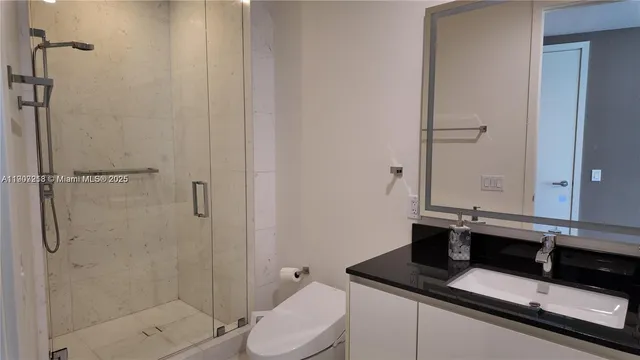 a bathroom with a granite countertop sink a toilet and shower