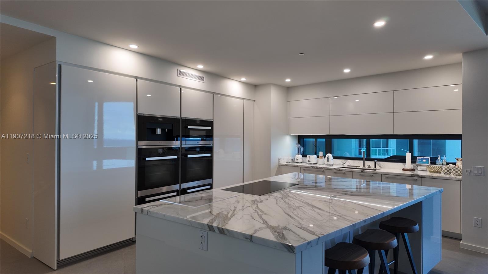 18555 Collins Avenue, Unit 905 Sunny Isles Beach, FL 33160 - Photo 7 of 38 a kitchen with stainless steel appliances granite countertop a sink and a refrigerator
