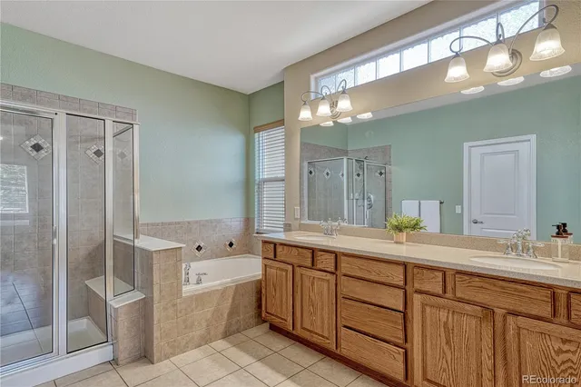 a spacious bathroom with a double vanity sink a large mirror and a bathtub