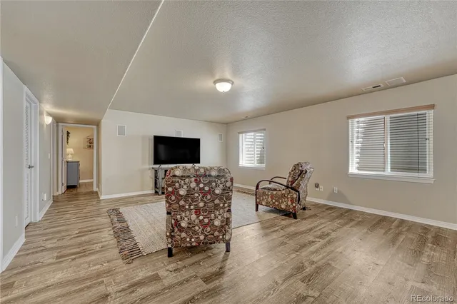 a living room with furniture a flat screen tv and wooden floor