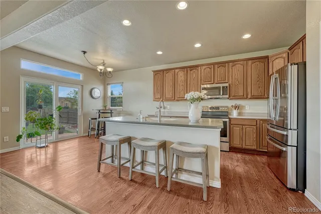 a kitchen with stainless steel appliances granite countertop a refrigerator a stove top oven a sink dishwasher and white cabinets with wooden floor