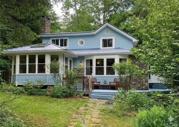 a view of house with yard outdoor seating and covered with trees