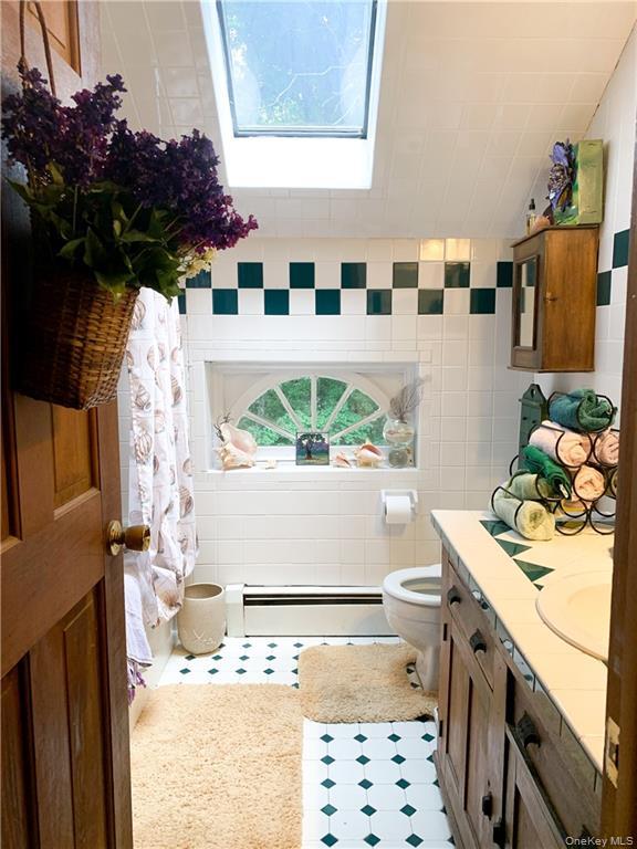 446 Shandelee Road Livingston Manor, NY 12758 - Photo 23 of 33 Full bathroom with a baseboard heating unit, vanity, tile walls, and light tile patterned floors