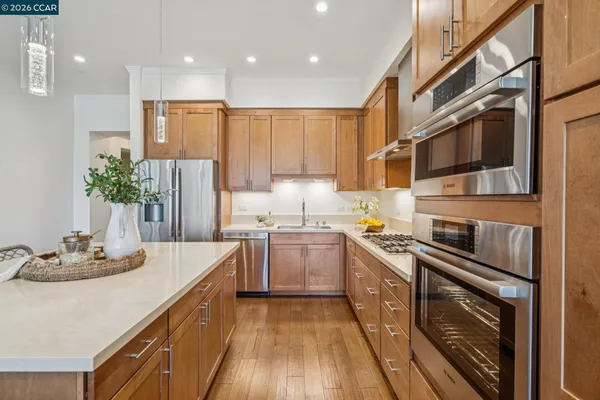 a kitchen with stainless steel appliances granite countertop a refrigerator a stove and a wooden floors