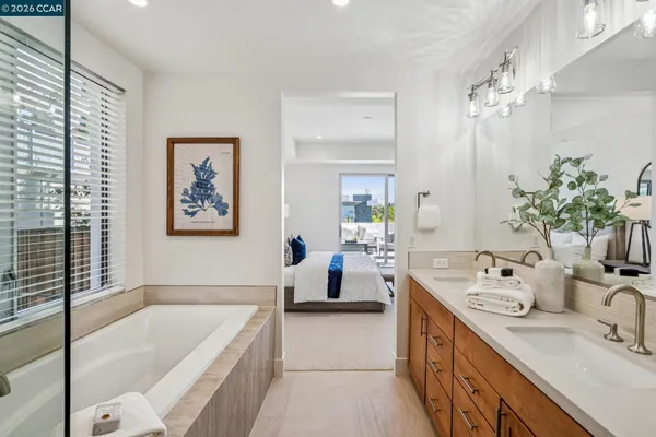 a spacious en suite bathroom with a granite countertop tub sink and mirror