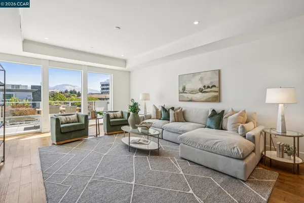 a living room with furniture large window and kitchen view