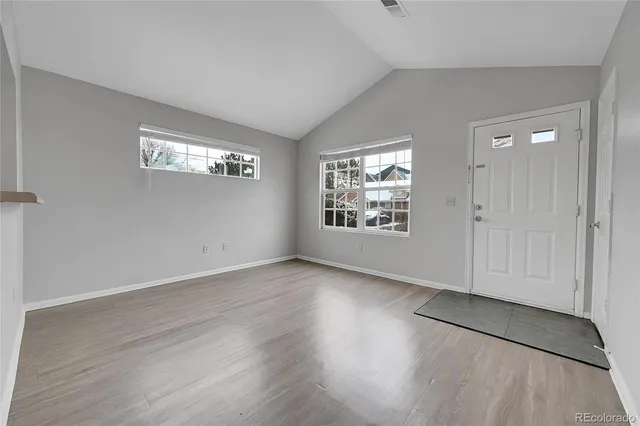 an empty room with wooden floor and windows