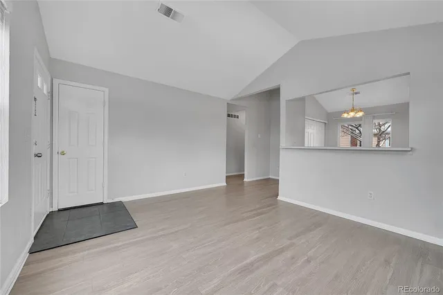 a view of an empty room with wooden floor and a mirror