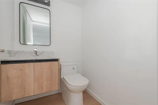 a bathroom with a toilet a sink a mirror and vanity
