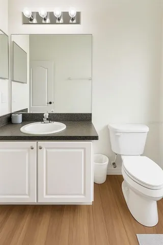 a bathroom with a granite countertop toilet sink and mirror