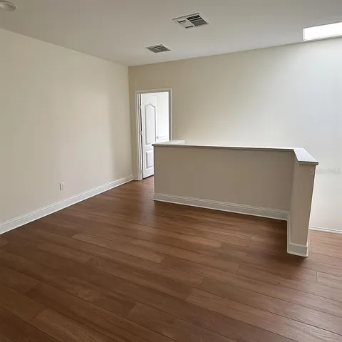 a view of an empty room with wooden floor