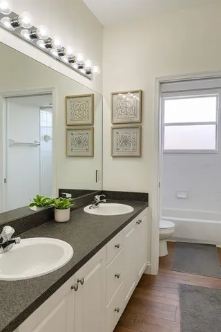 a bathroom with a granite countertop bathtub sink vanity mirror and toilet