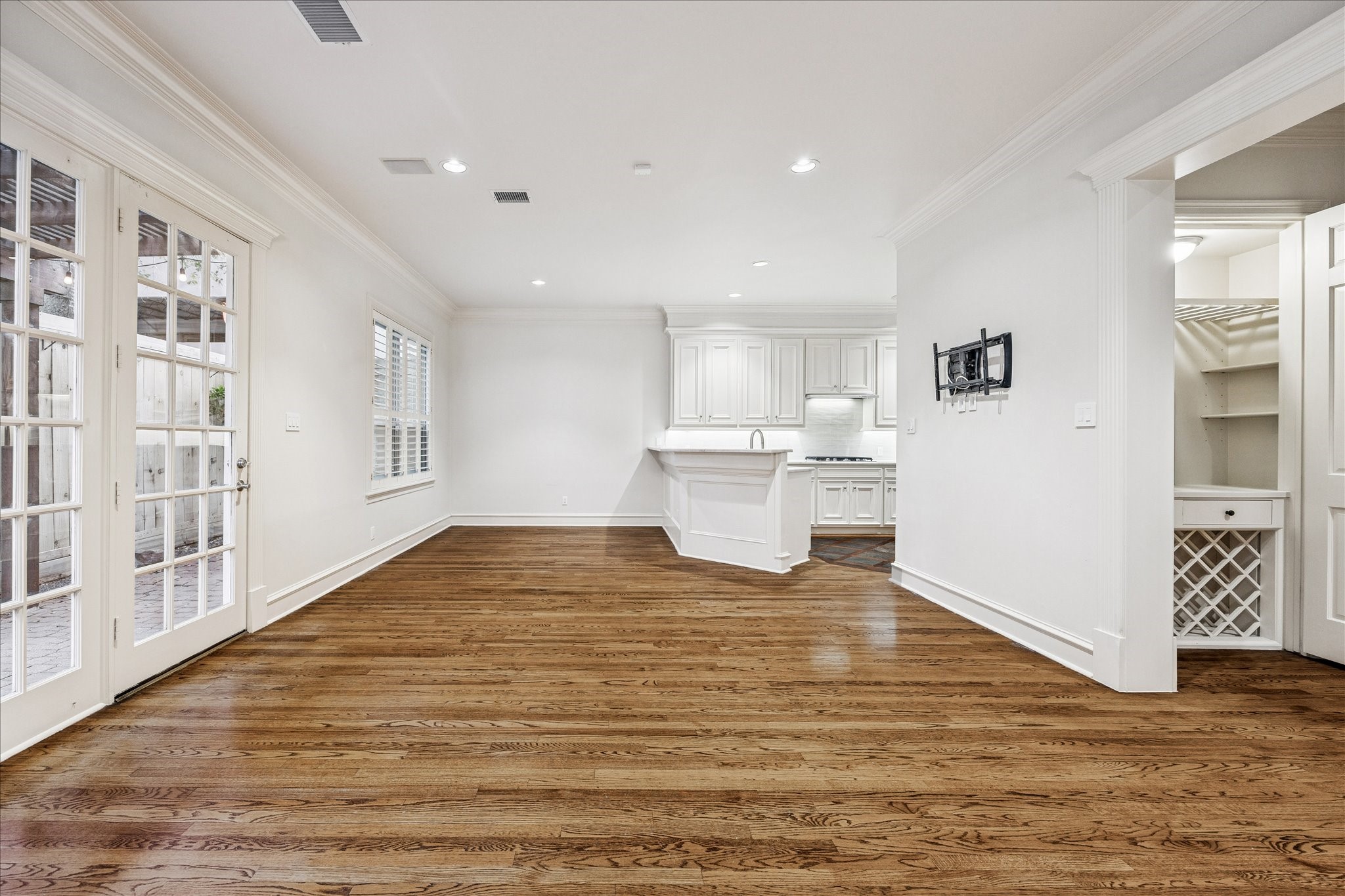 5823 Augusta Court Houston, TX 77057 - Photo 13 of 44 This bright, open-concept space features hardwood floors, recessed lighting, and French doors leading to a patio. The kitchen boasts white cabinetry and a central island, providing a modern and inviting atmosphere.
