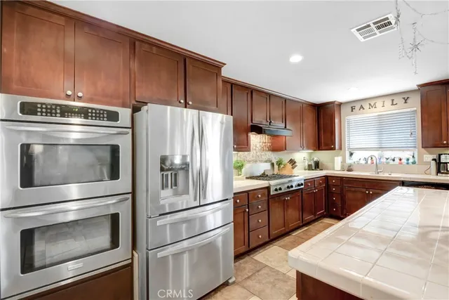 a kitchen with a sink a stove a refrigerator cabinets and dining table