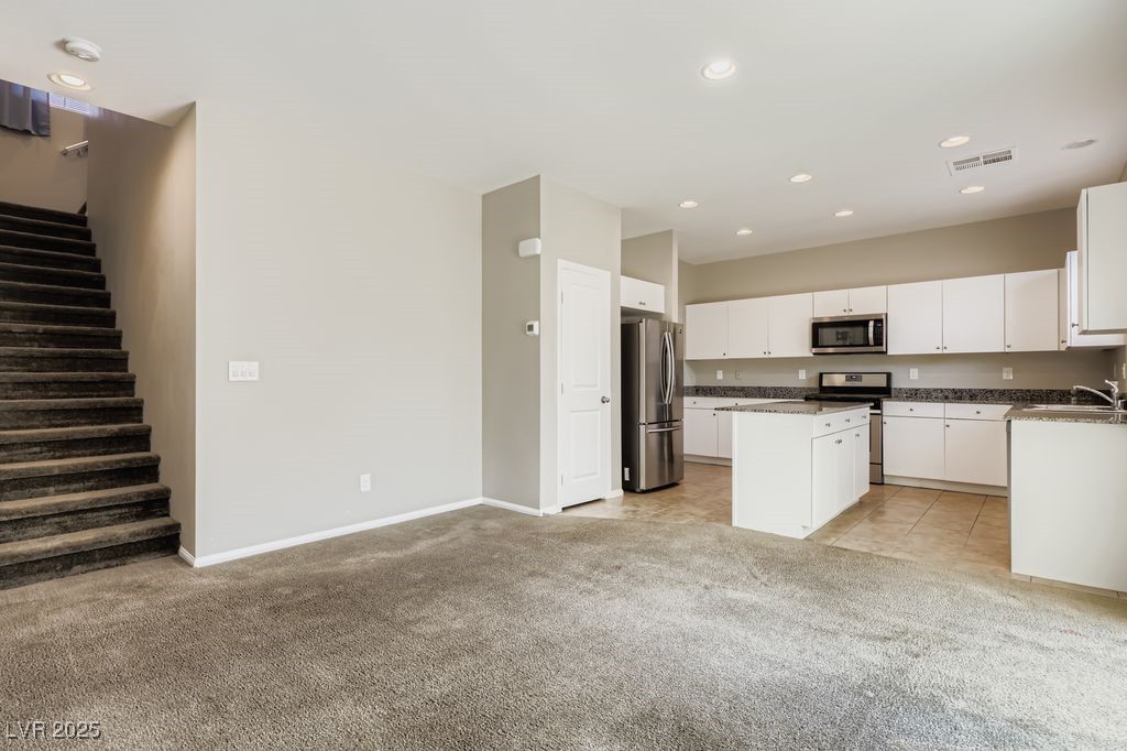 5712 Wishing Coin Court North Las Vegas, NV 89031 - Photo 20 of 24 Kitchen with white cabinetry, appliances with stainless steel finishes, recessed lighting, light colored carpet, and a kitchen island