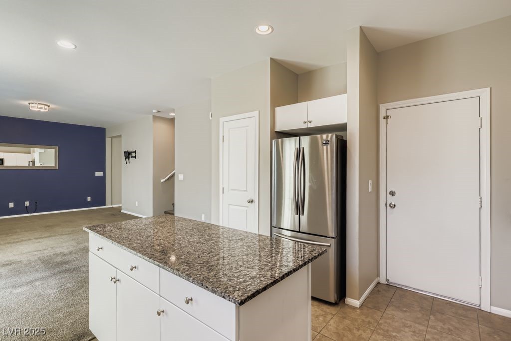 5712 Wishing Coin Court North Las Vegas, NV 89031 - Photo 21 of 24 Kitchen with freestanding refrigerator, dark stone countertops, a kitchen island, recessed lighting, and white cabinets