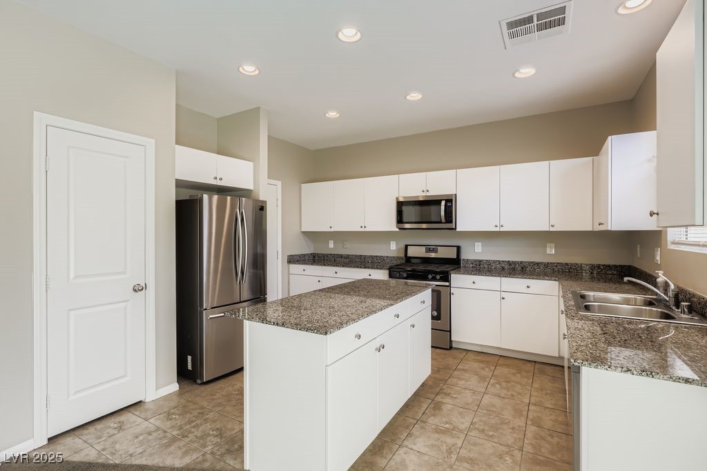 5712 Wishing Coin Court North Las Vegas, NV 89031 - Photo 6 of 24 Kitchen with stainless steel appliances, white cabinetry, a center island, dark stone countertops, and recessed lighting
