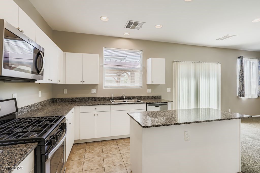 5712 Wishing Coin Court North Las Vegas, NV 89031 - Photo 7 of 24 Kitchen with appliances with stainless steel finishes, a kitchen island, recessed lighting, white cabinets, and dark stone countertops