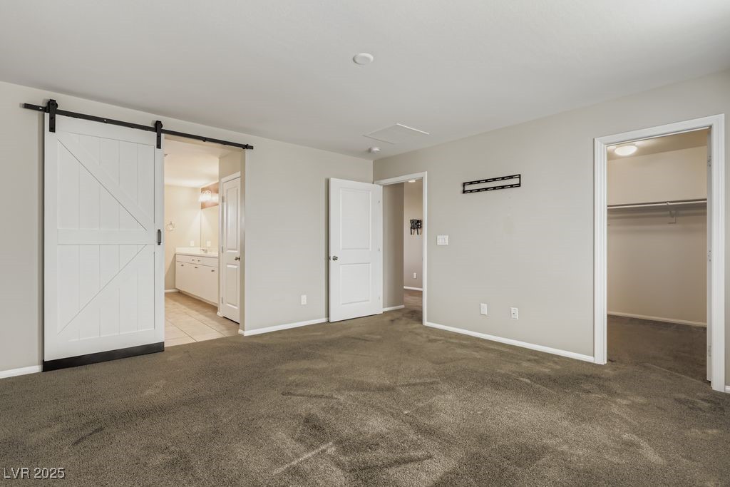 5712 Wishing Coin Court North Las Vegas, NV 89031 - Photo 10 of 24 Primary bedroom with a spacious closet, carpet, a barn door, and ensuite bath