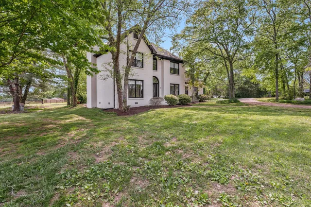 a view of a house with a big yard and large trees