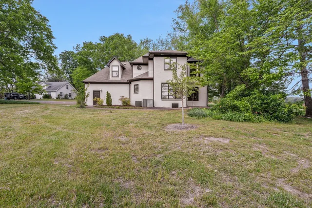 a view of a house with a big yard and large trees