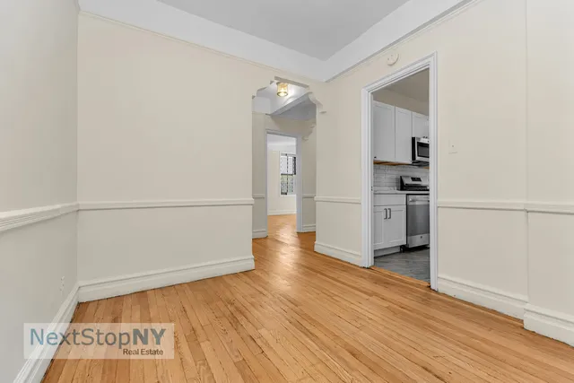 a view of an empty room with window and chandelier fan