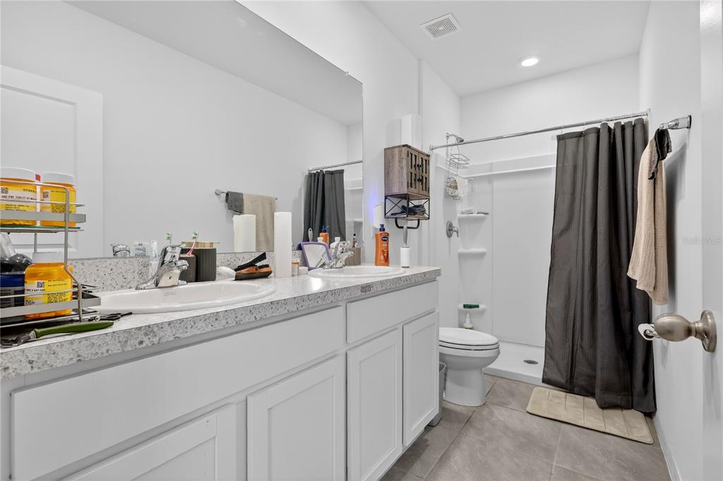 16632 Grotto Steam Place Wimauma, FL 33598 - Photo 15 of 42 a bathroom with a double vanity sink toilet and shower
