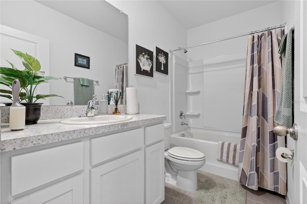 16632 Grotto Steam Place Wimauma, FL 33598 - Photo 25 of 42 a bathroom with a granite countertop sink toilet a large mirror a shower and a bathtub