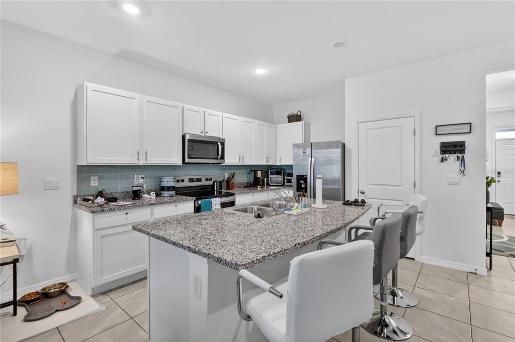 16632 Grotto Steam Place Wimauma, FL 33598 - Photo 8 of 42 a kitchen with granite countertop sink refrigerator and cabinets