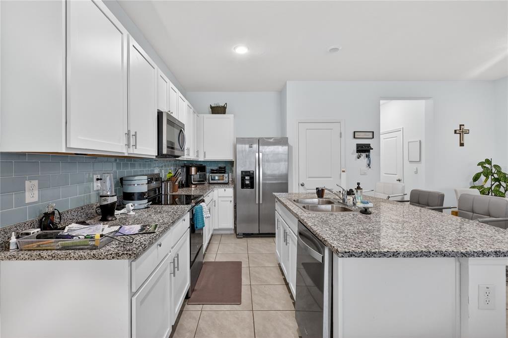 16632 Grotto Steam Place Wimauma, FL 33598 - Photo 10 of 42 a kitchen with granite countertop kitchen island stainless steel appliances a sink stove and cabinets