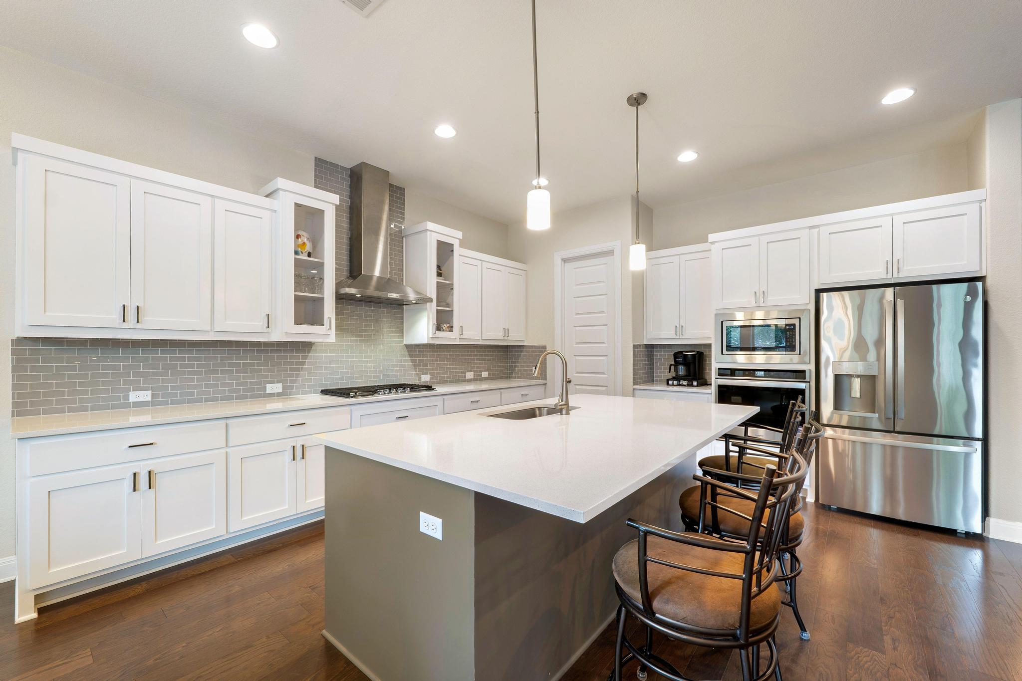 1009 Legacy Crossing Georgetown, TX 78628 - Photo 15 of 40 A chef's dream, this kitchen boasts white cabinetry, a spacious island, and gleaming stainless steel appliances.