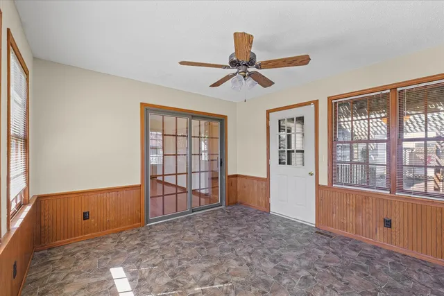 an empty room with windows and ceiling fan