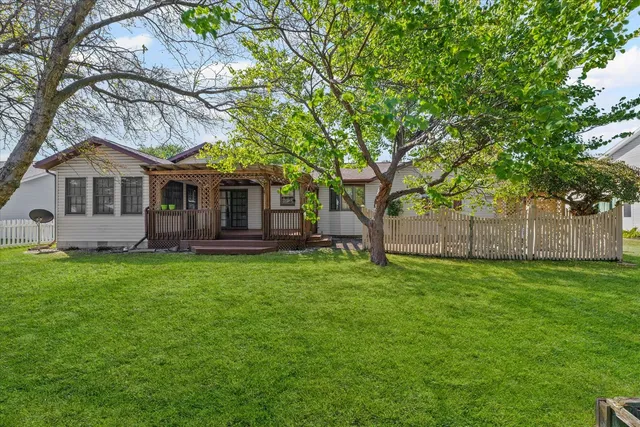 a white house with a big yard plants and large trees