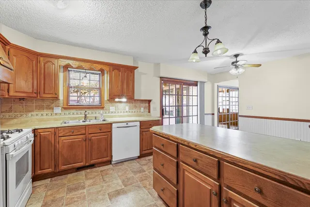 a large kitchen with stainless steel appliances granite countertop a sink dishwasher with a dining table and chairs
