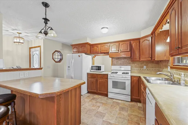 a open kitchen with stainless steel appliances granite countertop a sink a stove and a refrigerator