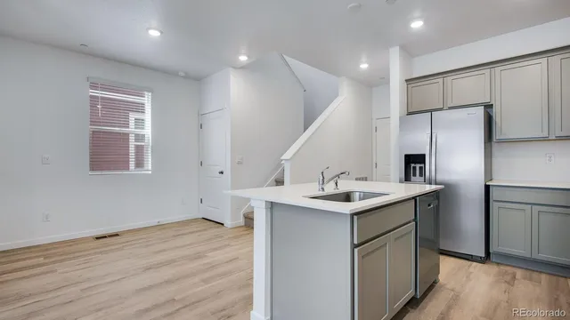 a kitchen with a sink stainless steel appliances and wooden floor