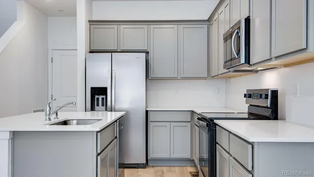 a kitchen with stainless steel appliances a sink a refrigerator and cabinets