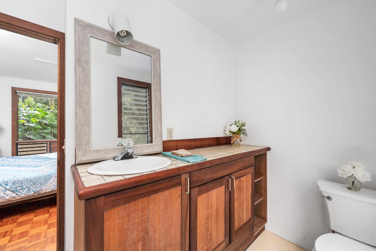 88-2497 Milolii Road Captain Cook, HI 96704 - Photo 16 of 30 a bathroom with a granite countertop sink a toilet and mirror