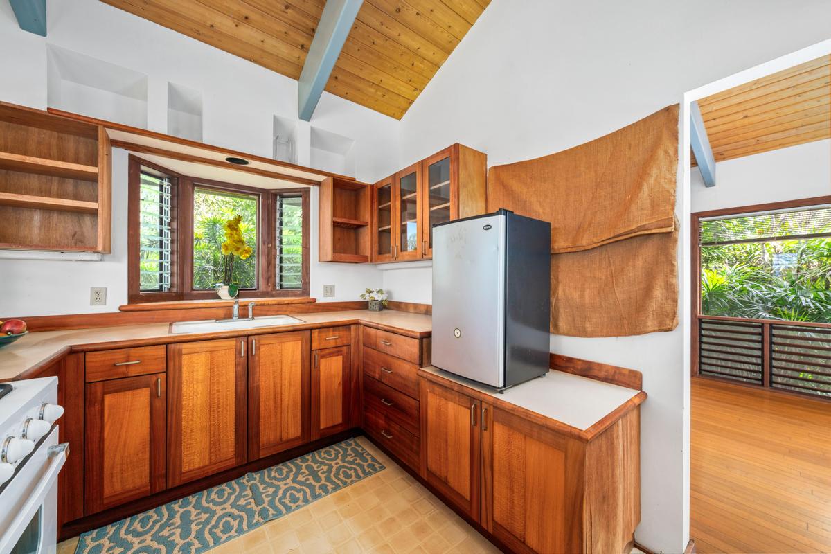 88-2497 Milolii Road Captain Cook, HI 96704 - Photo 10 of 30 a kitchen with stainless steel appliances granite countertop a refrigerator a sink dishwasher a stove and a dining table with wooden floor