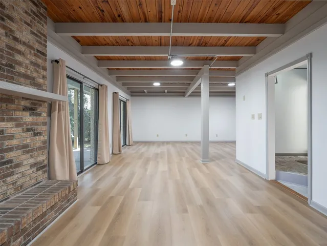a view of an empty room with wooden floor fireplace and a window