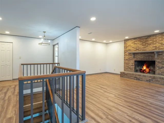 a view of an empty room with wooden floor and windows